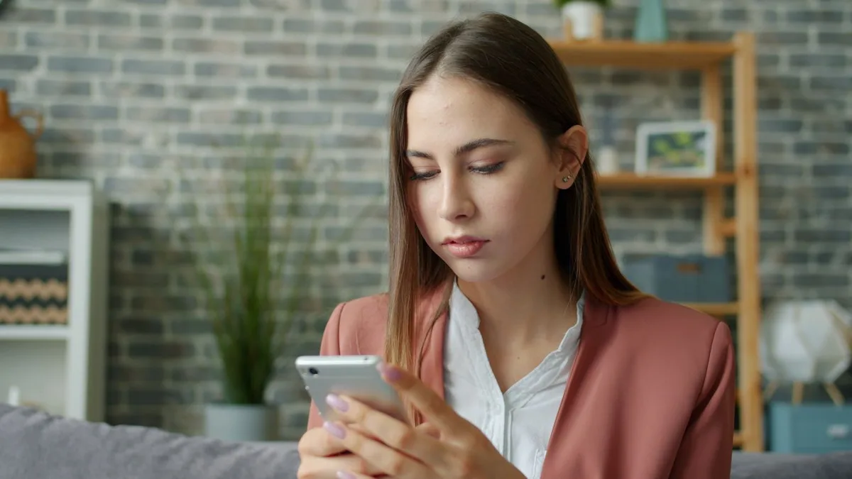 A woman browsing a smartphone in a furnished living room