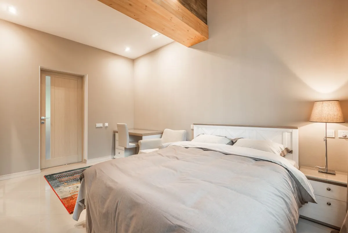 A furnished bedroom with a neatly made bed and bedside furnishings