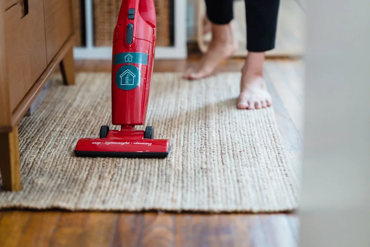 A person using a red vacuum cleaner on a carpet