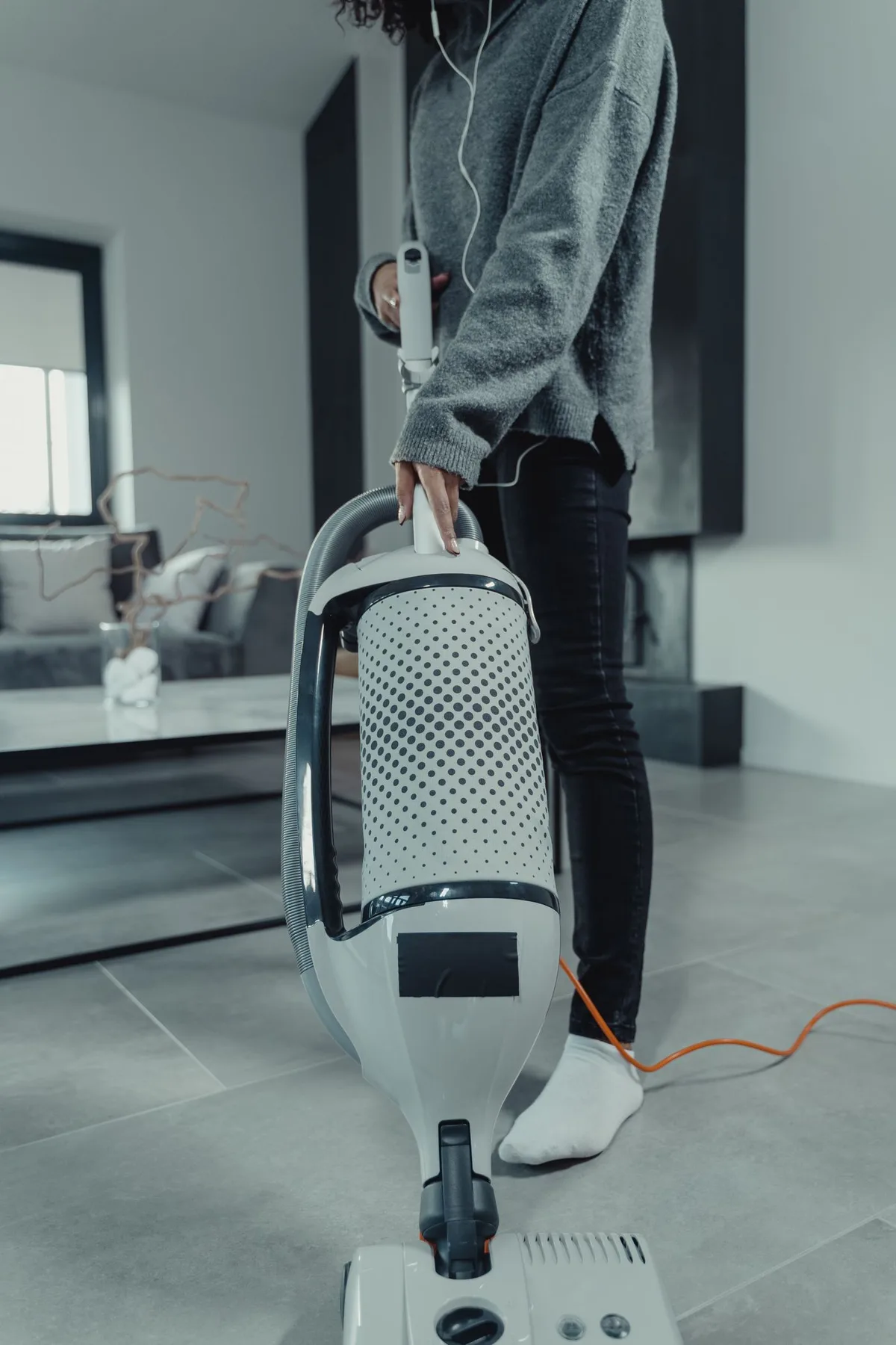 A person vacuuming the floor in a furnished living room